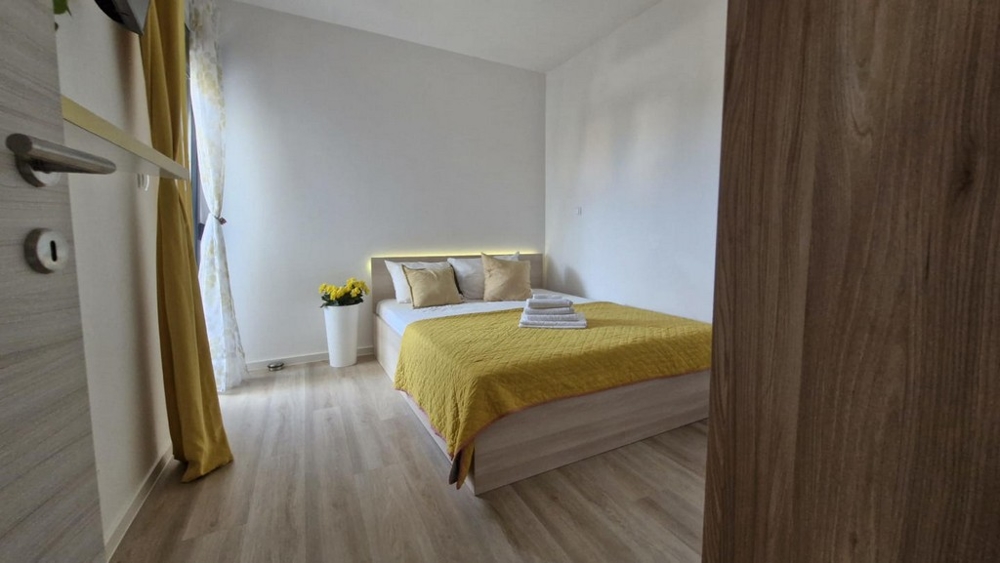 Camera da letto con letto matrimoniale, copriletto giallo e decorazioni