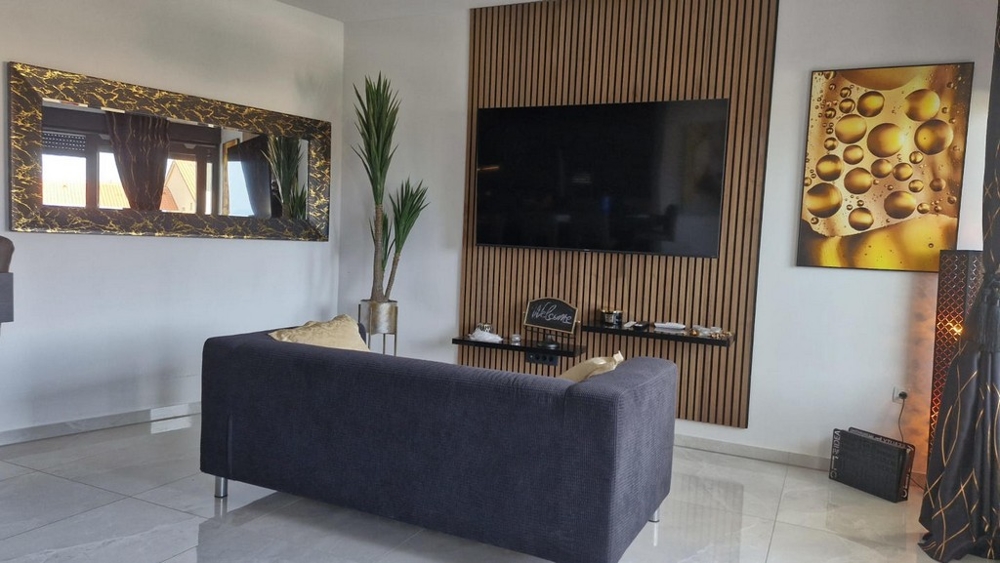 Soggiorno con grande televisore, divano ed elementi decorativi