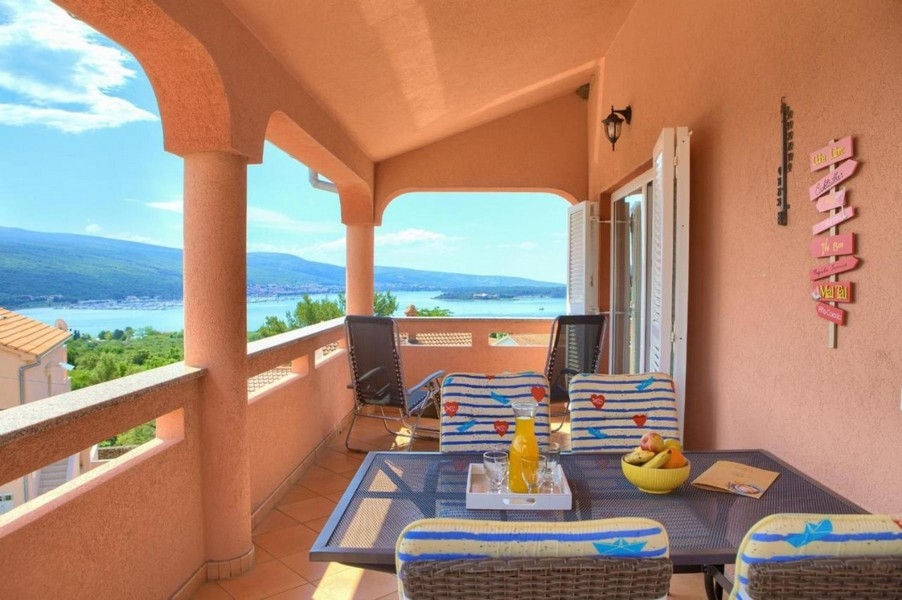 Terrazza coperta con tavolo e sedie, vista mare sullo sfondo