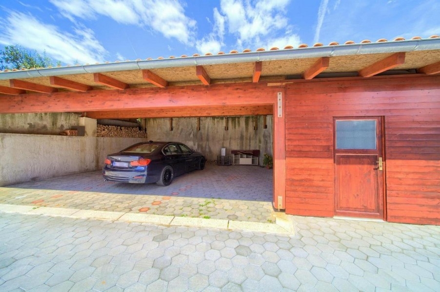 Posto auto coperto con un'auto parcheggiata e rivestimento in legno