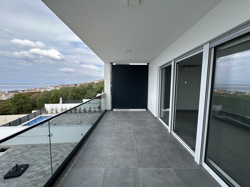 Lunga loggia con parapetto in vetro e vista sulla piscina e sul mare