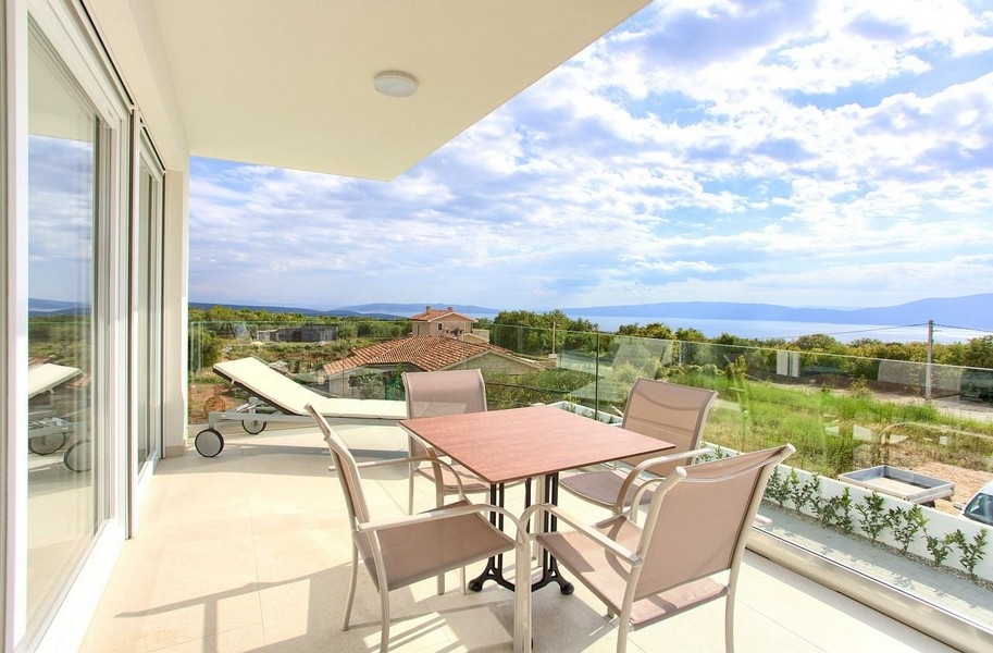 Terrazza con tavolo e lettino davanti all'ampia vista sulla baia