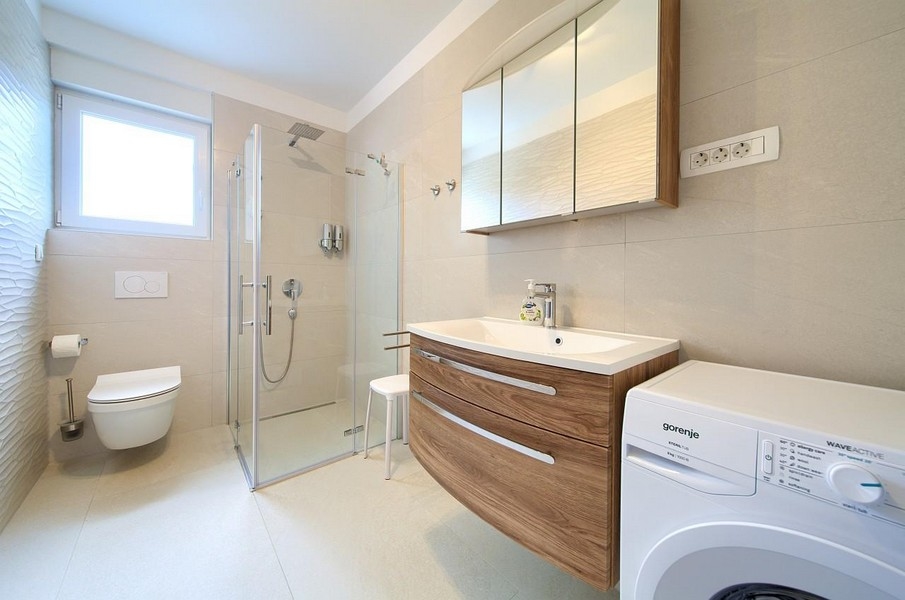 Bagno moderno con doccia e lavatrice.