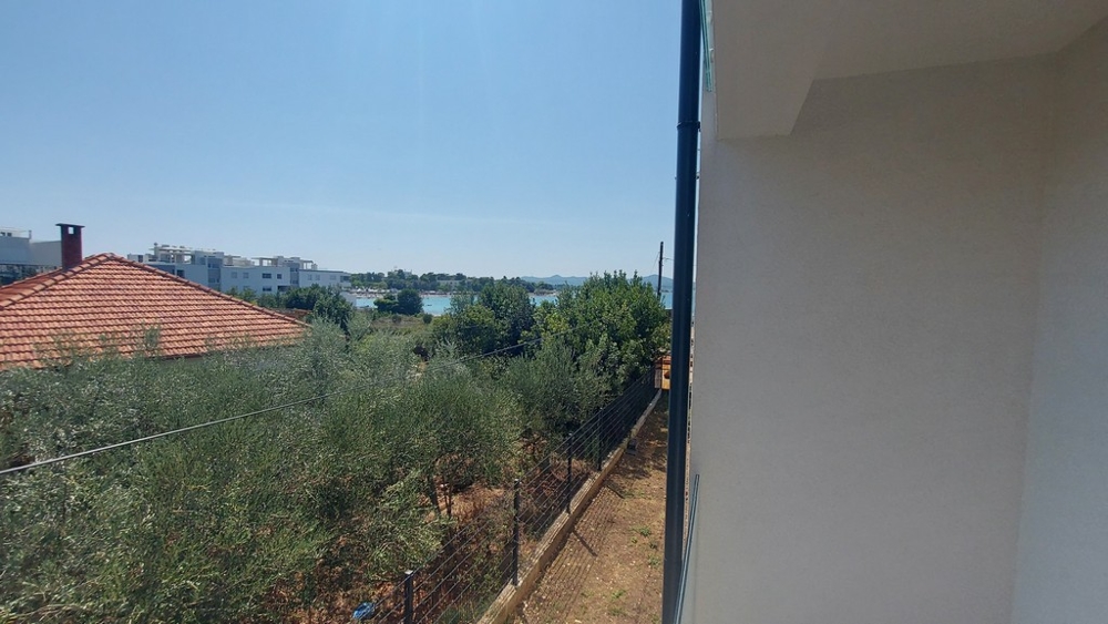 Vista lungo la parete della casa, oltre gli ulivi, verso la baia
