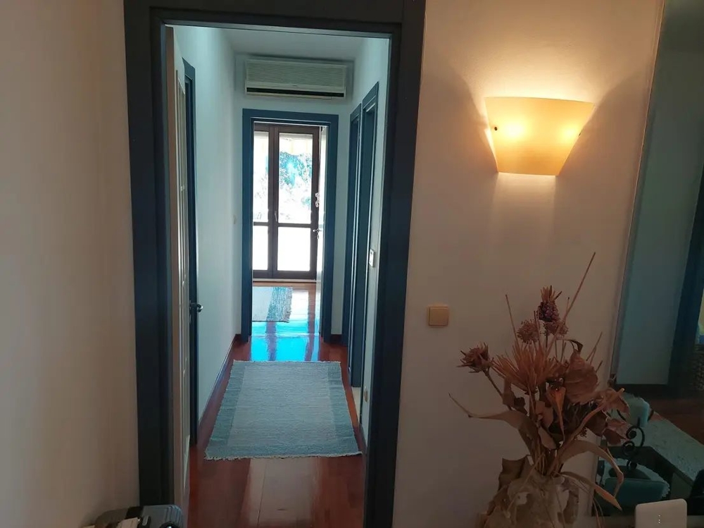 Corridoio con pareti chiare e pavimento in legno, ingresso arredato in modo moderno