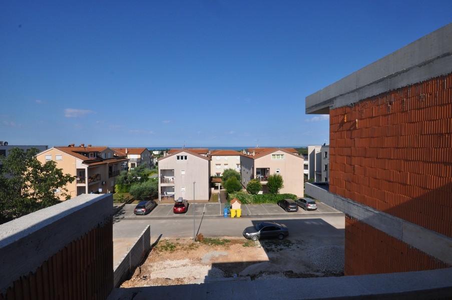 Vista dalla costruzione al grezzo sui posti auto e sulle case fino al mare