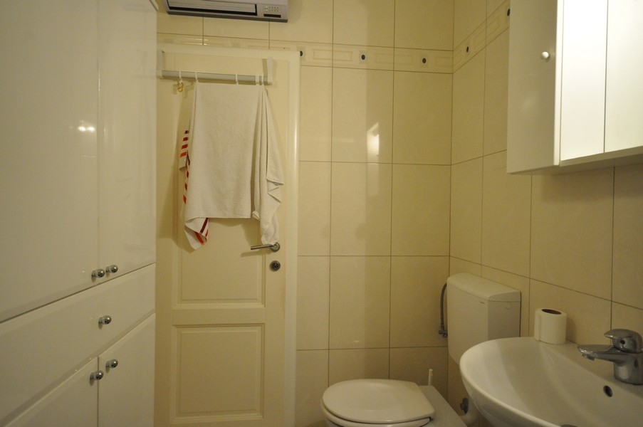 Bagno con WC, lavabo, portasciugamani alla porta, piastrelle chiare, dotazioni moderne