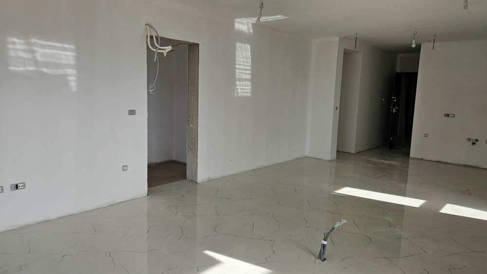 Locale non finito con piastrelle chiare a pavimento, pronto per le ulteriori finiture interne