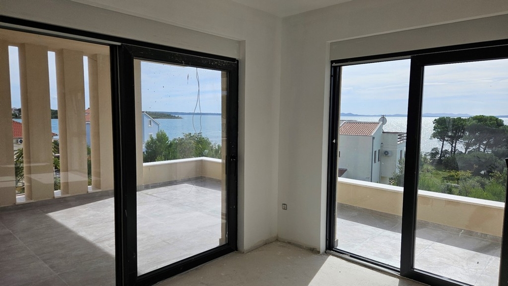 Zona giorno con grandi vetrate che mostrano la vista mare e il balcone