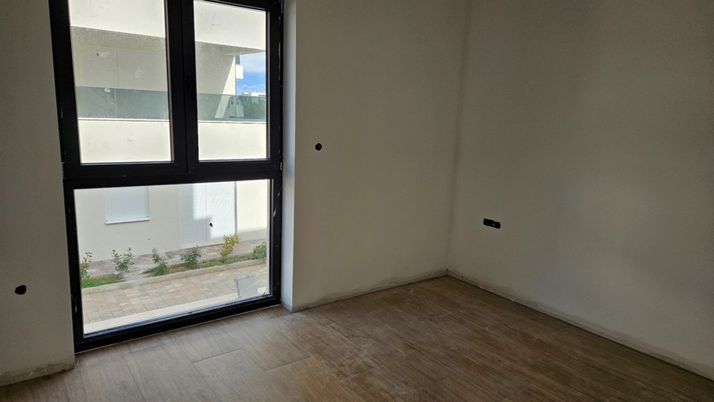 Un altro locale con grandi finestre, la cui vista mostra un edificio moderno e un'area pavimentata.