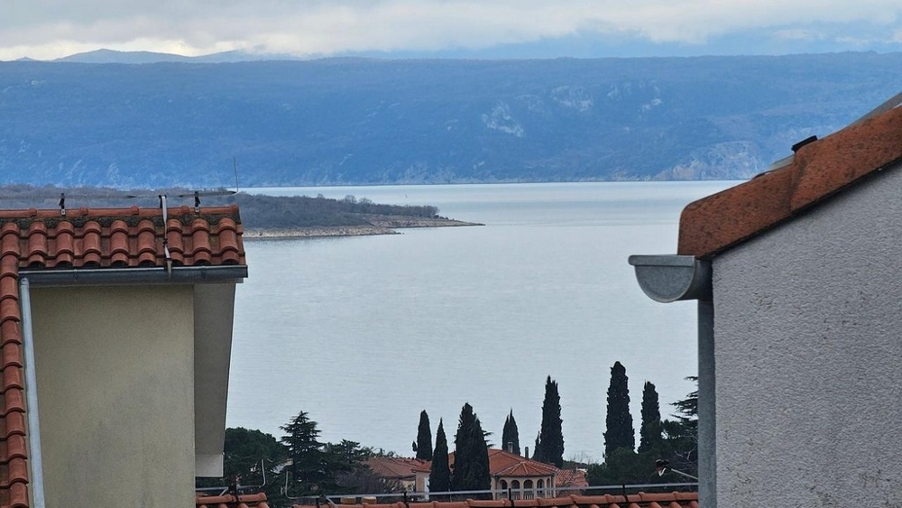 Vista tra due case sulla baia e sulle montagne