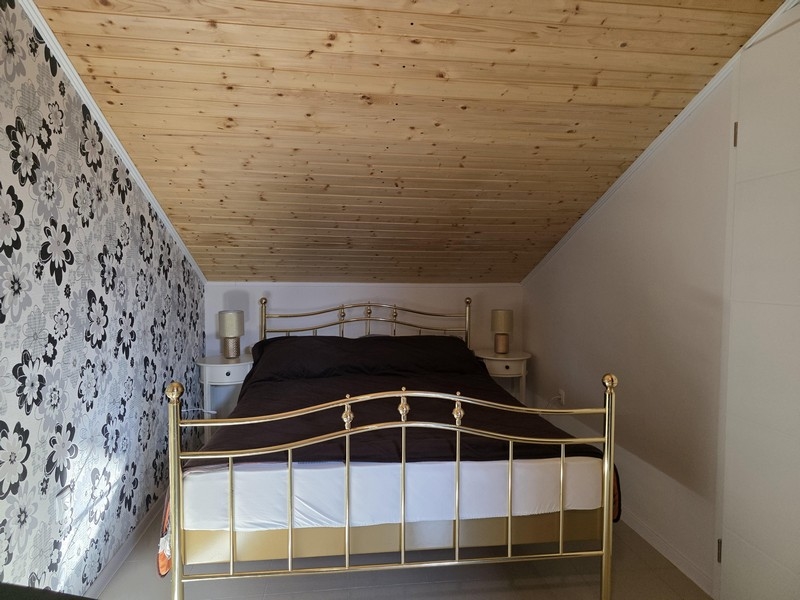 Camera da letto nel sottotetto con soffitto mansardato e letto matrimoniale