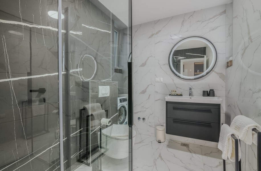Bagno con doccia moderna in vetro e piastrelle in marmo