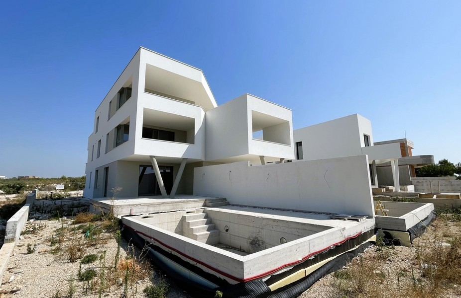 Edificio nuovo bianco con vasca della piscina al grezzo davanti