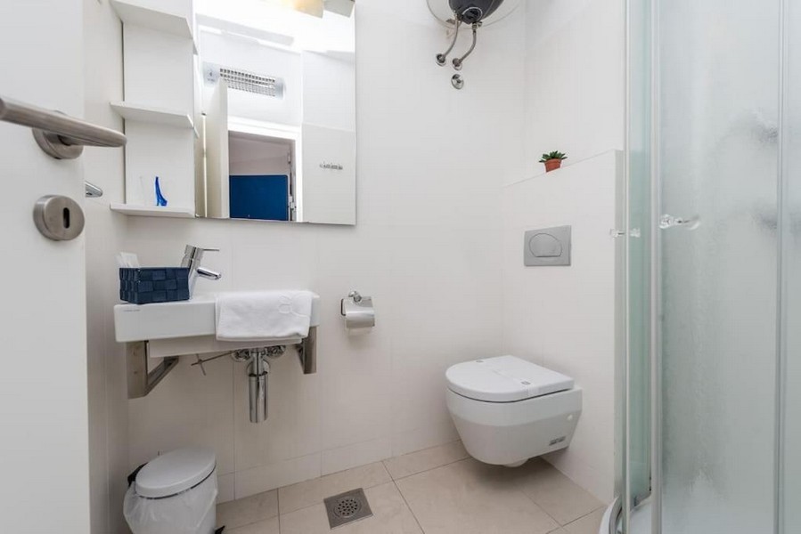 Bagno con doccia e piastrelle bianche