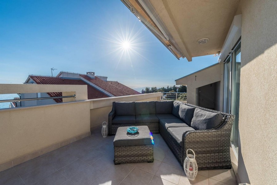 Terrazza sul tetto soleggiata con zona salotto e vista mare