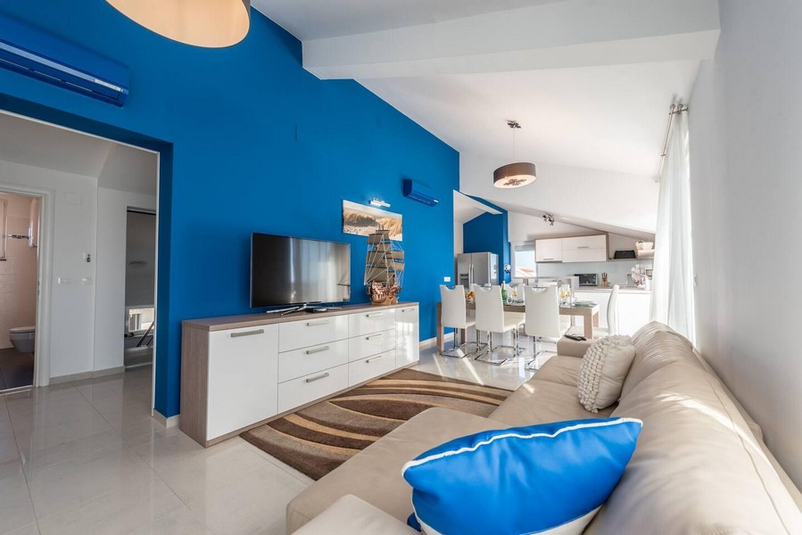 Zona giorno con parete blu e cucina aperta