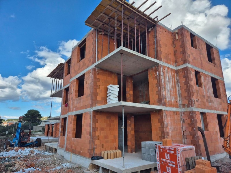 Nuova costruzione di un edificio residenziale di tre piani con balconi aperti e materiali di cantiere