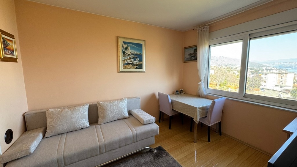 Soggiorno con divano, tavolo e grande finestra con vista mare