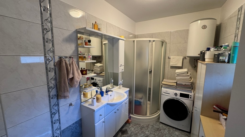 Bagno con doccia, lavatrice e lavabo con specchio