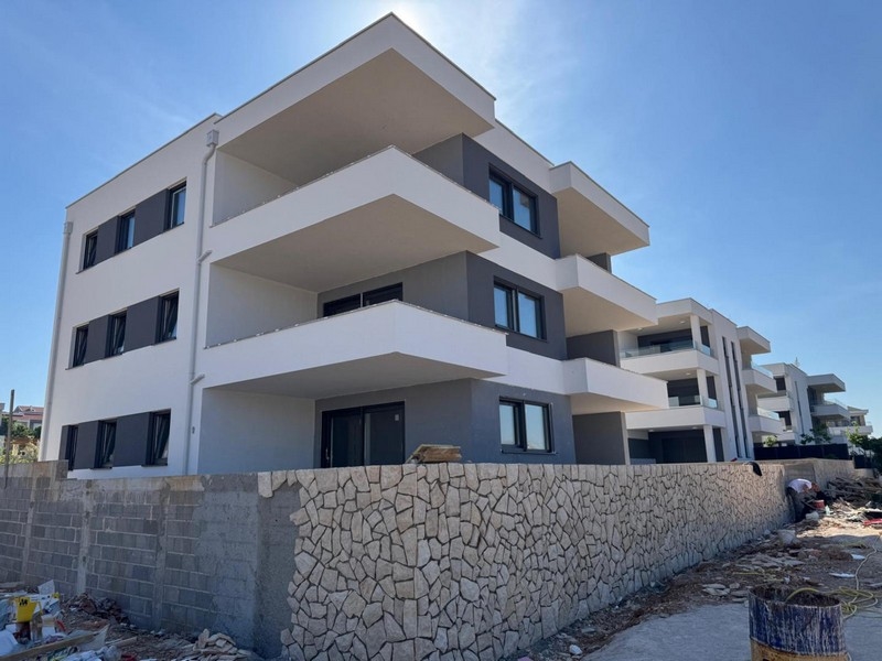 Edificio nuovo con fasce di balconi bianche dietro il muro in pietra naturale