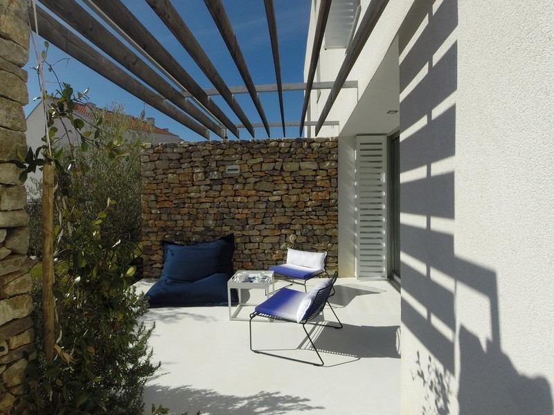 Terrazza sotto la pergola con pouf davanti al muro a secco
