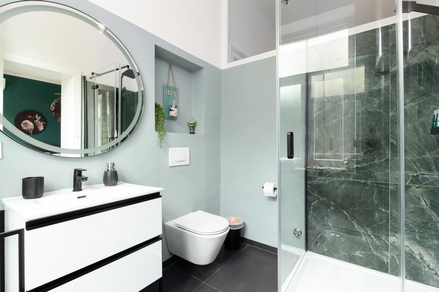 Bagno con specchio rotondo e doccia in vetro