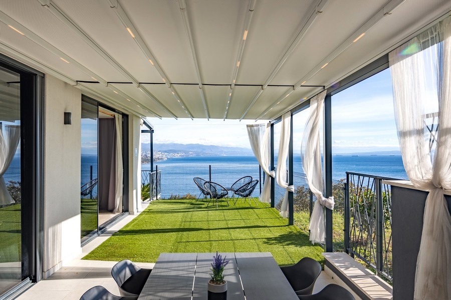 Terrazza coperta con giardino e vista mare panoramica.