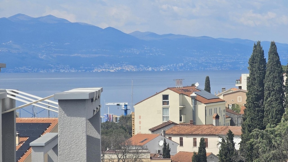 Vista sopra i tetti e i cipressi fino al mare e alla catena montuosa