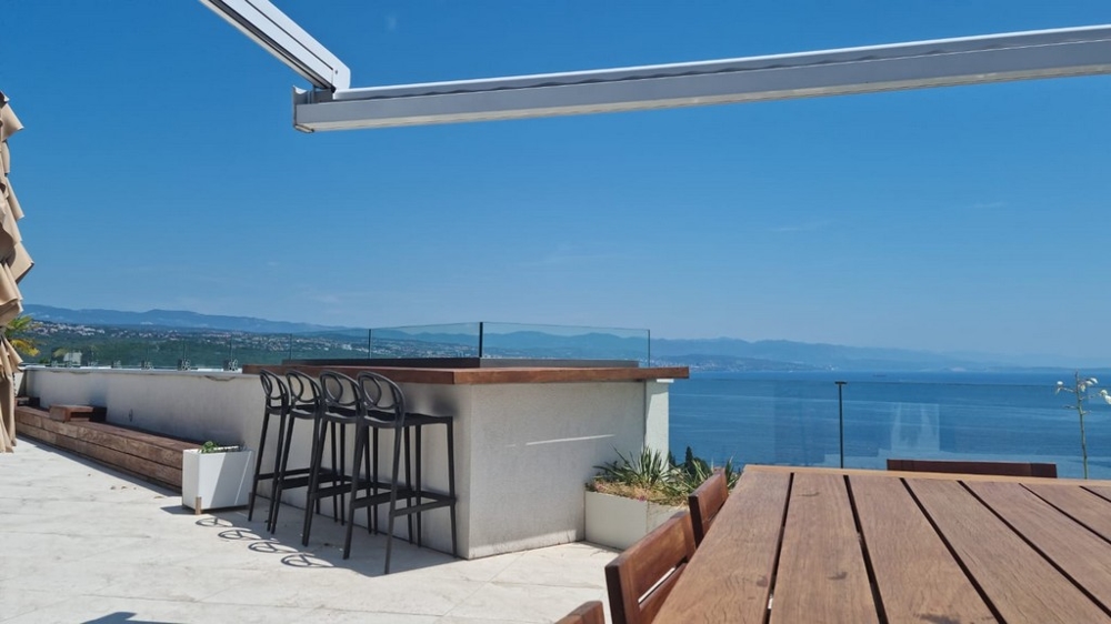 Terrazza sul tetto con bancone e sgabelli da bar sopra la baia