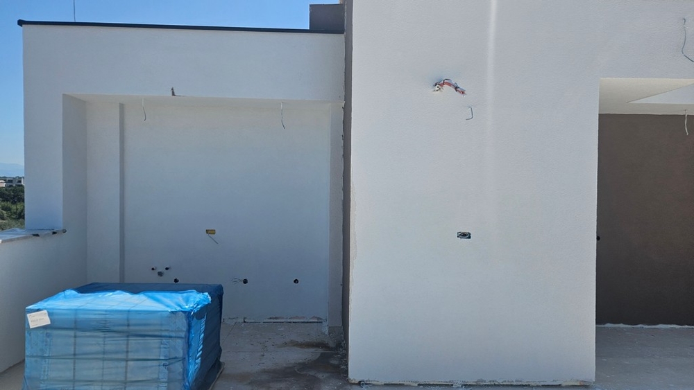 Interno al grezzo con grandi finestre scorrevoli e vista sul mare