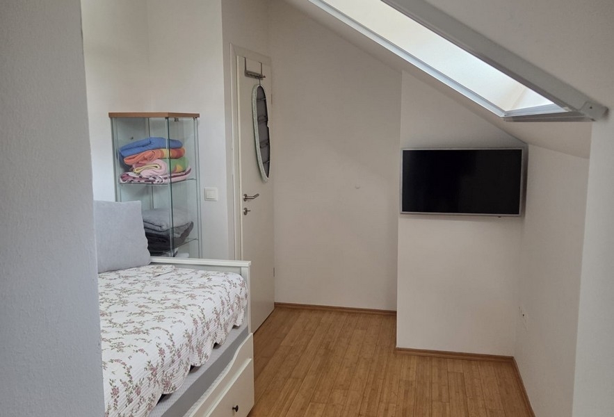 Camera degli ospiti con letto, TV e soffitto spiovente