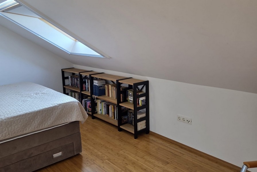 Camera da letto con soffitto spiovente e librerie