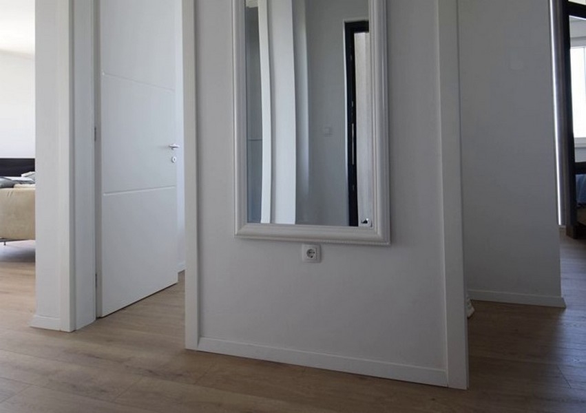 Corridoio con specchio a parete e porta aperta di una stanza
