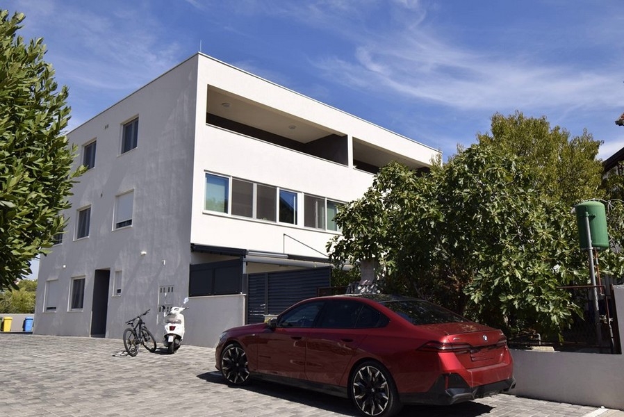 Edificio residenziale con loggia al piano superiore e posti auto davanti