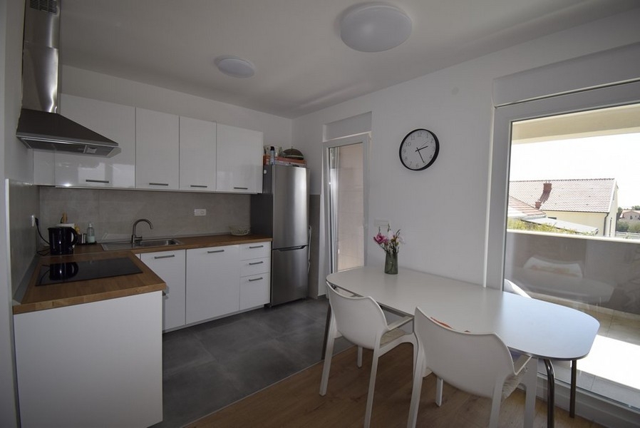 Cucina a blocco con tavolo da pranzo e porta-finestra sul balcone
