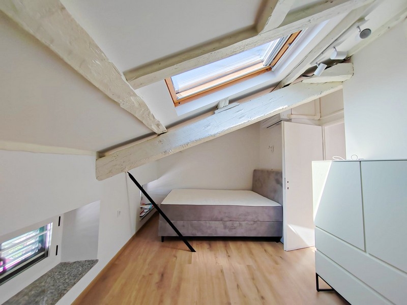 Seconda camera da letto nel sottotetto con letto e travi del tetto
