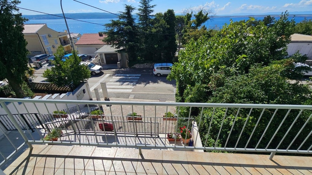Balcone con vasi di fiori e vista oltre la strada fino al mare