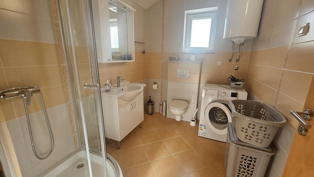 Bagno con doccia, lavatrice e finestra