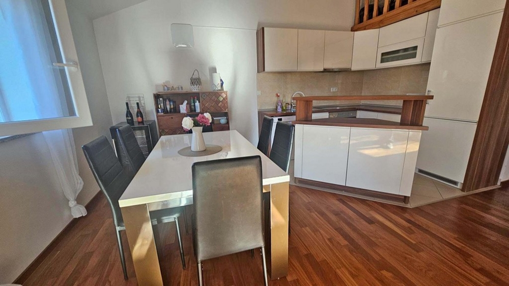 Zona pranzo con tavolo e accesso alla cucina moderna