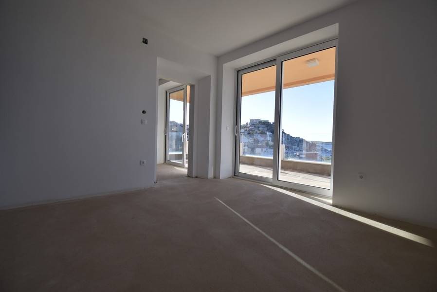 Stanza luminosa con grandi finestre e accesso al balcone