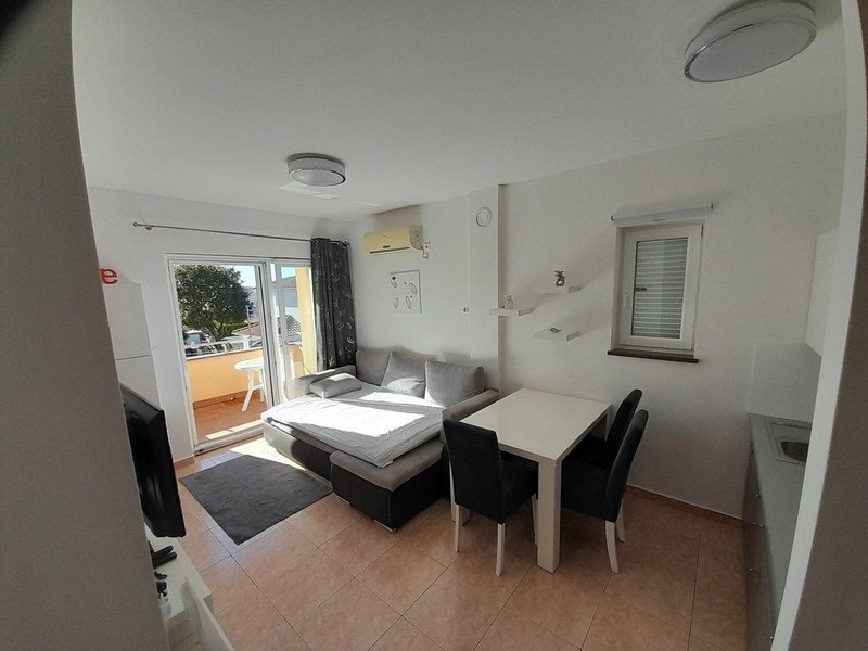 Zona giorno con divano, tavolo da pranzo e accesso al balcone con vista mare