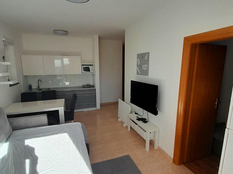 Soggiorno con televisore, tavolo da pranzo e accesso alla camera da letto