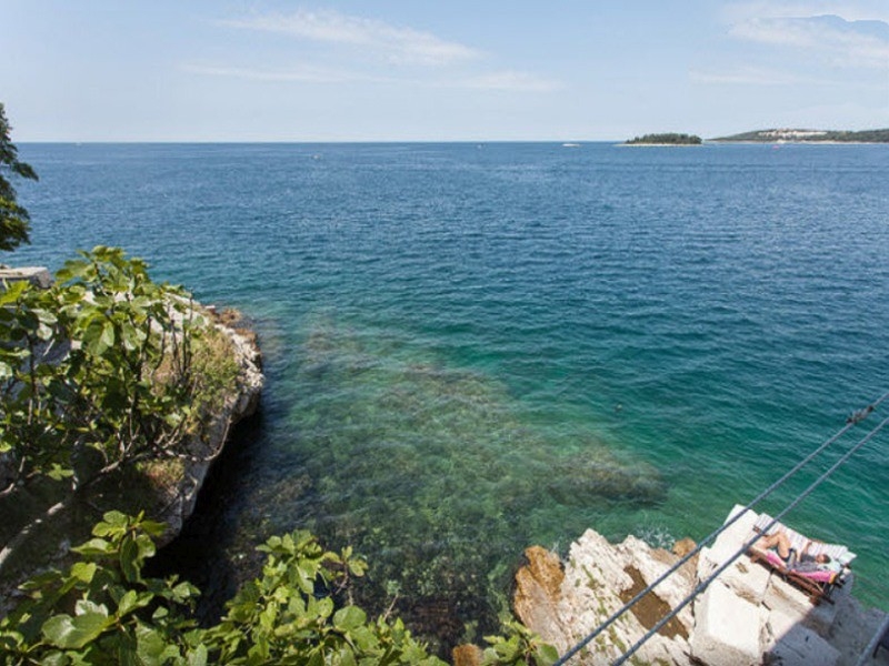 Costa rocciosa con acqua limpida e piattaforma per i bagni