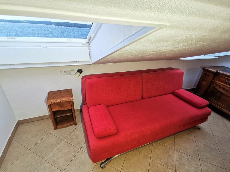 Zona salotto con divano rosso e vista mare