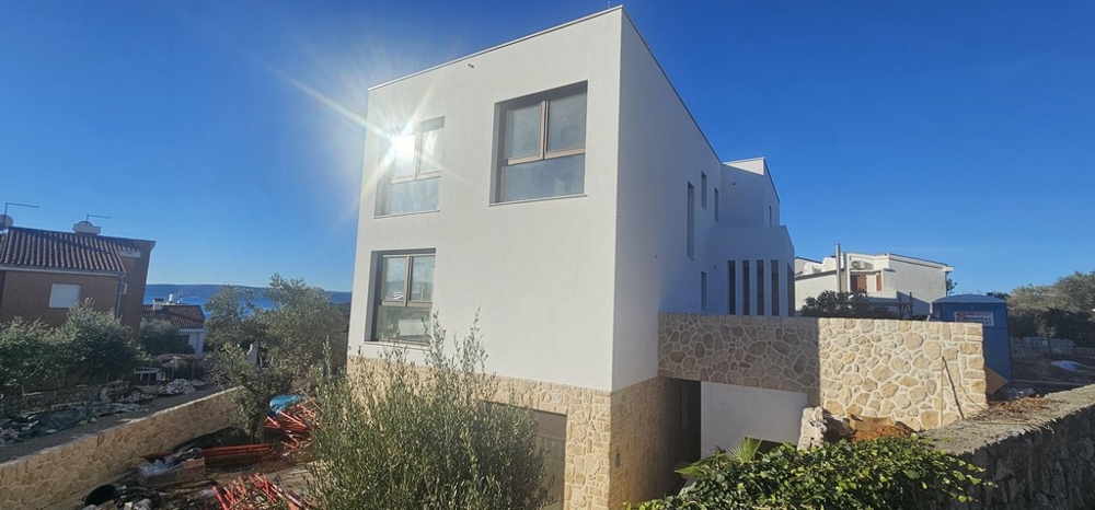 Casa bianca con zoccolo in pietra naturale in controluce