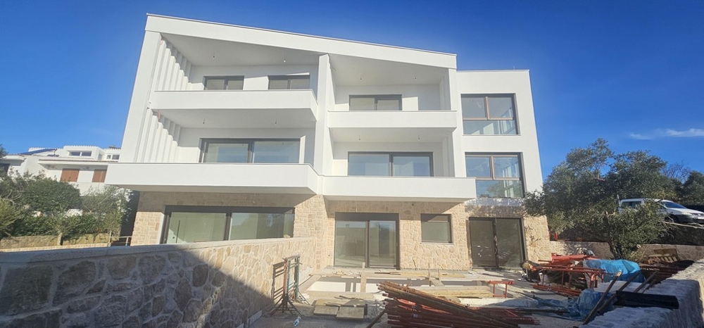 Casa nuova con balconi e zoccolo in pietra naturale contro il cielo azzurro