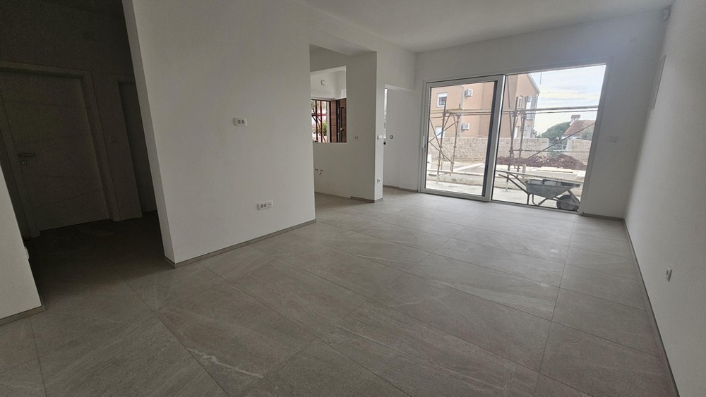 Zona giorno con pavimento in piastrelle e porta scorrevole sulla terrazza