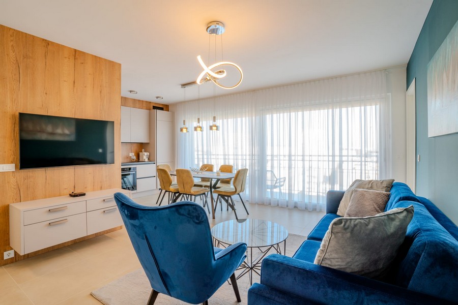 Zona giorno aperta con divano, cucina e accesso alla terrazza