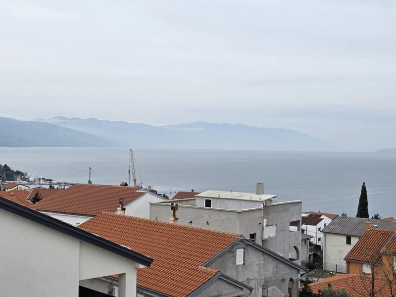 Tetti in tegole davanti alla baia nella foschia con gru sulla riva